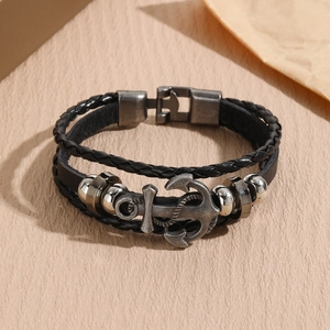 Detail of vintage multilayer leather bracelet with metal anchor pendant and braided cords