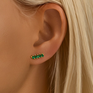 Macro shot of S925 silver gold-plated earring with green marquise-cut gems on model ear