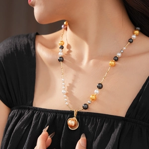 Detail of pearl necklace featuring gold, black and white pearls with a zircon pendant
