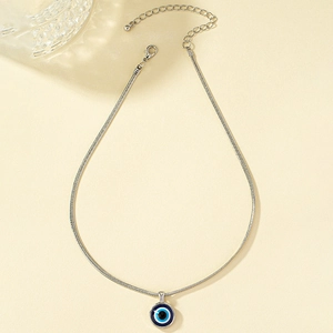 Macro view of silver snake chain necklace with blue evil eye pendant and lobster clasp