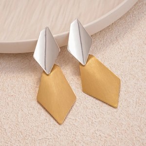Macro detail of geometric earrings showing silver mirror finish and brushed gold texture