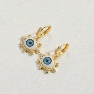 Close-up of golden evil eye earrings with blue enamel and sparkling zircon stones