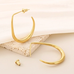 Minimalist U-shaped gold earrings in polished titanium steel on stone pedestal