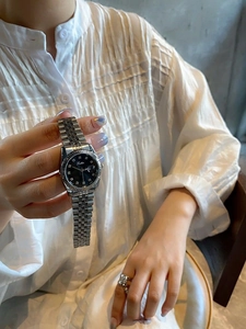 Detail of silver steel watch featuring black diamond dial and Scottie logo on wrist