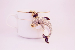 Macro shot of dolphin keychain with sparkling rhinestones, golden crown, and enamel details