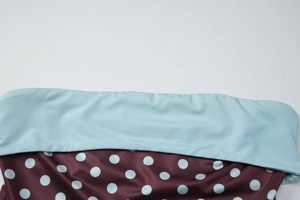 Détail de la taille bleu clair jointe à un tissu marron à pois avec des coutures fines