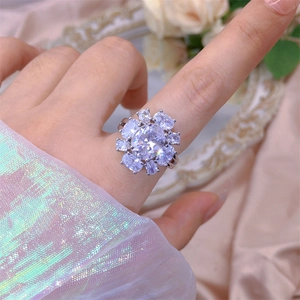 Primer plano de anillo floral de plata con circonitas sobre un fondo de seda rosa