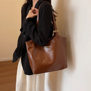 Brown high-quality soft leather tote bag for women featuring a golden metal accent piece