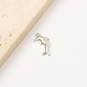 Detailed view of silver dolphin pendant on textured stone for DIY jewelry making