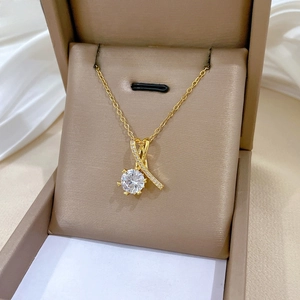 Vue détaillée du collier en titane doré avec pendentif cœur croisé en zircon et cristaux brillants