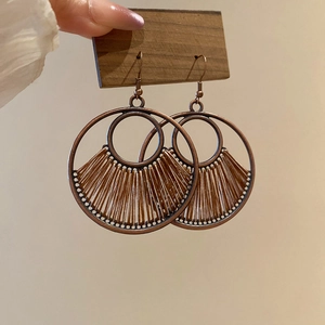 Detail of bohemian hollow round pendant earrings with brown woven cord on vintage bronze