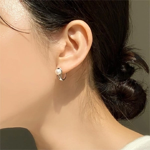 Minimalist 925 sterling silver pearl hoop earrings worn by a model in a side view