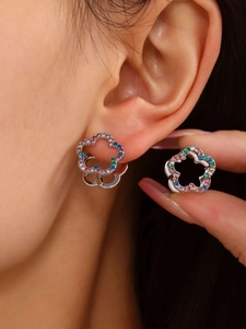 Detailed view of silver flower earrings with colorful zircons worn on a model ear