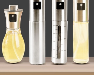 Detail view of various stainless steel and glass oil spray bottles with measurement scales