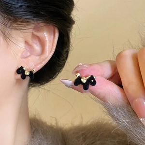 Primer plano de pendientes de cachorro negros flocados con detalles de metal dorado