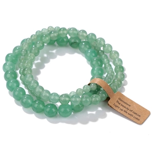 Primer plano de tres pulseras apiladas de cuentas de piedras verdes con etiquetas naturales