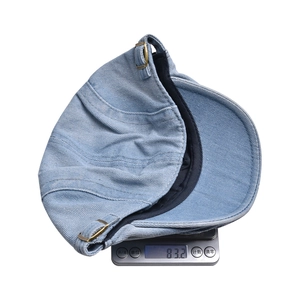 Macro shot of light blue denim ivy cap on a digital scale showing weight of 83.2g