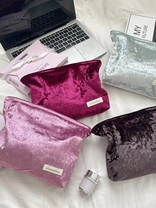Premium crushed velvet makeup bags in four colors on a white minimalist desk background