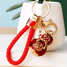 Close-up of red woven keychain with gold Fu character gourd charm and heart detail
