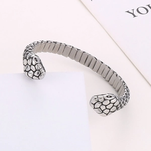 Macro detail showing dual snake heads and textured scales of the stainless steel cuff bracelet