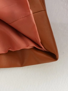 Close-up of brown PU leather blazer showing stitching detail and orange fabric lining
