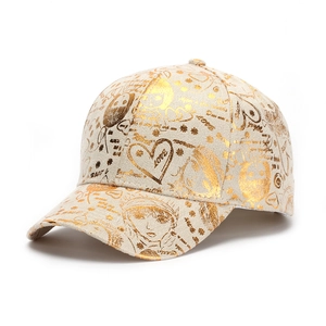 Détail d'une casquette beige avec motifs de fille graffiti et cœurs dorés