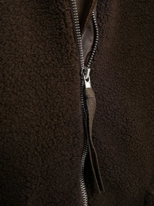 Detailed close-up of the metal zipper and fuzzy teddy fleece texture on a dark brown jacket