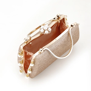 Detailed shot of golden glitter evening bag with pearl flower and beaded tassels