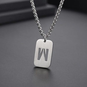Détail macro du pendentif rectangulaire argenté avec lettre M évidée sur chaîne