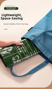 Foldable green shopping bag being tucked into a canvas tote to show its compact size