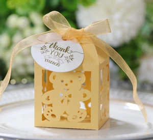 Detail of yellow hollow bear candy box with golden ribbon and thank you tag on a plate