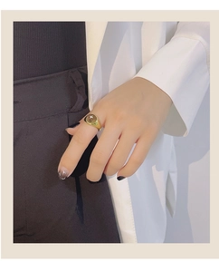 Close-up of gold ring with star motif dark gemstone worn on finger in minimalist style