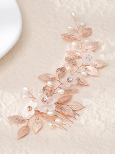 Detailed close-up of rose gold hair comb with pearls, frosted flowers and metal leaves