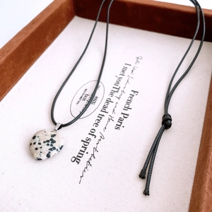 Gros plan détaillé du pendentif coeur en jaspe dalmatien sur un cordon noir élégant