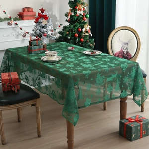 Green lace Christmas tablecloth with festive snowflake and reindeer patterns on a table