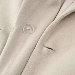 Gros plan d'un manteau en laine beige avec détails de boutons et coutures soignées