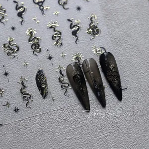 Macro detail of dark gothic nail stickers with gold snake, sun, and star patterns