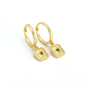 Gold eight-pointed star earrings with green gemstone insets on a white background