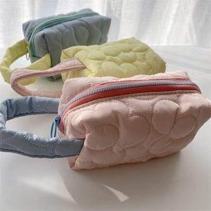 Three quilted floral organizers in pink, yellow and blue with colorful contrast zippers