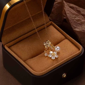 Close-up of five-petal zircon flower and pearl pendant on a gold necklace