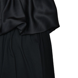 Close-up of black satin and knit fabric texture contrast on a waist-cinching dress