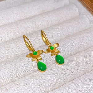 Detail view of vintage flower drop earrings with green resin stones on a velvet tray