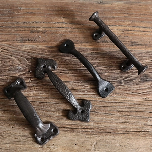 Set of four vintage matte black cast iron door handles on a rustic wood background