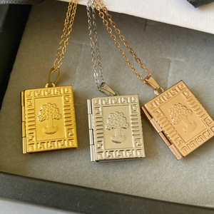 Detailed macro view of book-shaped locket pendants in gold, silver, and rose gold finishes