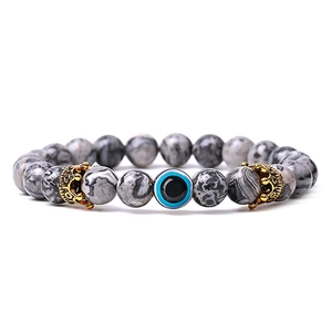 Detail of grey marble beads bracelet with blue evil eye and golden crown charms