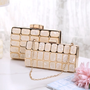 Close-up of elegant acrylic clutch bags with gold metal frames and pearl texture