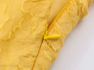 Detail of invisible zipper on yellow vacation dress with textured floral embroidery