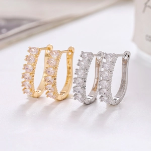 Detail of C-shaped gold and silver earrings with drop-shaped cubic zirconia inlay