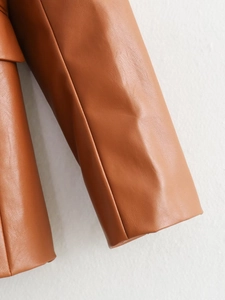Detailed view of caramel brown faux leather fabric with fine pebbled texture and neat stitching