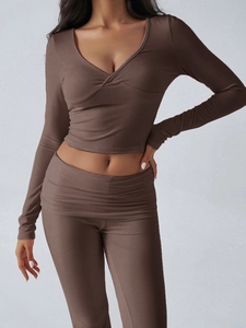 Detail view of the V-neck crop top with crossover pleats and high waist trousers in dark brown